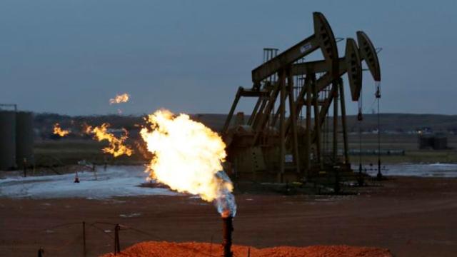Dec. 17, 2014. Oil pumps work behind a natural gas flare near Watford City, N.D. (AP Photo/Eric Gay, File)